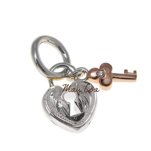 May include: A silver heart-shaped padlock charm with a key, featuring a diamond accent. The key and the loop are rose gold and silver. The padlock has a keyhole design and the text "Man Loa".