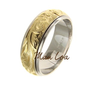 May include: A gold and silver wedding band with a floral design. The band is engraved with the words "Man Loa".