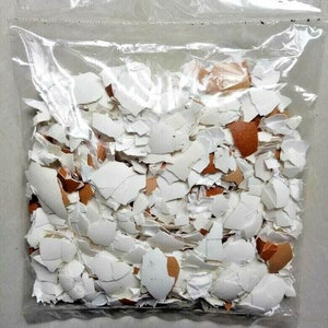 以下が含まれることがあります： 白い卵の殻と茶色の卵の殻を砕いたものが、透明なビニール袋に入っています。