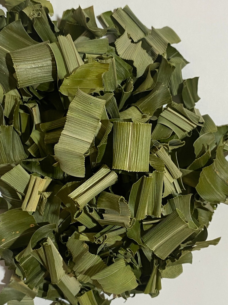 May include: Close-up of dried, chopped green leaves. The leaves are a muted green color and appear to be cut into various sizes. The texture of the leaves is visible, with prominent veins. The image is well-lit, highlighting the natural color and texture of the leaves.