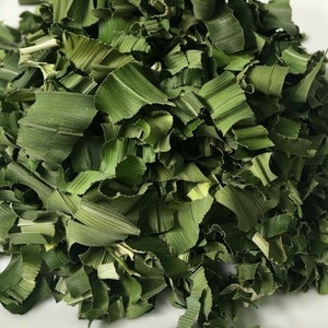 May include: Close-up of dried, chopped green pandan leaves. The leaves are a vibrant green color and have a textured appearance. The image shows a pile of the leaves, which are commonly used in Southeast Asian cuisine for flavoring and coloring.