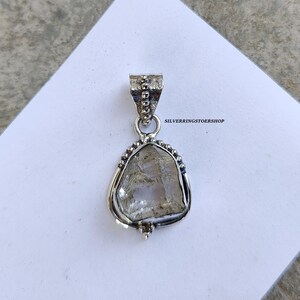 May include: A silver pendant featuring a clear, faceted quartz crystal set in a silver bezel. The pendant has a beaded bail and is ready to be added to a necklace.
