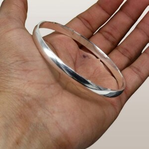 May include: A silver bangle bracelet with a smooth, polished finish.