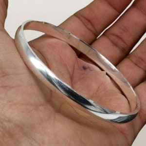May include: A simple silver bangle bracelet with a smooth, polished finish.