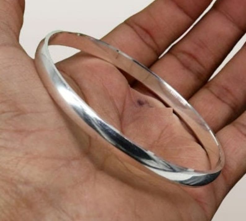 May include: A simple silver bangle bracelet with a smooth, polished finish.