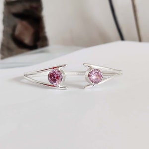 May include: A silver ring with two pink gemstones set in a delicate, open design.