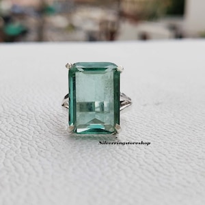 Può includere: Un anello d'argento con una grande pietra rettangolare di colore verde smeraldo.