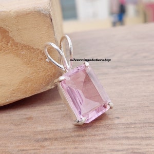 May include: A silver pendant with a light pink rectangular gemstone. The pendant has a simple bail design.