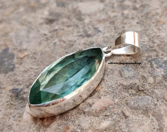 May include: A silver pendant featuring a marquise-shaped green gemstone. The pendant has a simple design and is perfect for adding a touch of elegance to any outfit.