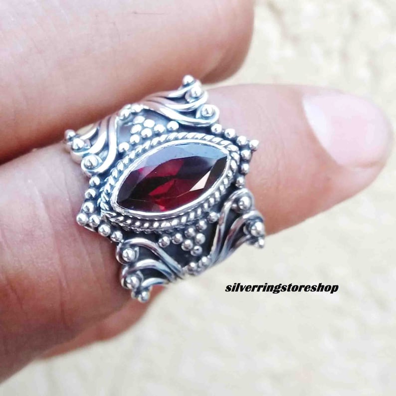 Puede incluir: Un anillo de plata con un dise&ntilde;o ornamentado y una piedra preciosa roja. El anillo est&aacute; engastado con una piedra de forma marquesa.