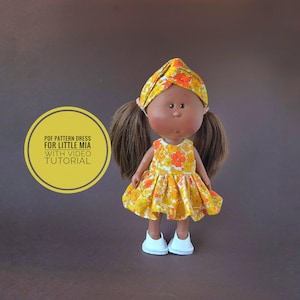 May include: A doll in a yellow floral dress and headband, with brown pigtails and white shoes. The text on the left reads "PDF PATTERN DRESS FOR LITTLE MIA WITH VIDEO TUTORIAL".