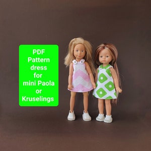 Peut inclure: Deux poupées vêtues de robes faites à la main. L'une porte une robe à chevrons rose et blanche, l'autre une robe à imprimé géométrique vert et blanc. Les deux poupées ont les cheveux blonds et portent des chaussures blanches. Un rectangle vert avec du texte blanc indique "PDF Pattern dress for mini Paola or Kruselings."