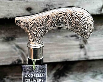 May include: A silver walking stick with an ornate handle and a black shaft. The handle has a floral design. A tag attached to the stick reads "UK Seller Delivery With In 3 Days Ministry of Antiques AIK SHAARR SAME DAX DRSDACH".