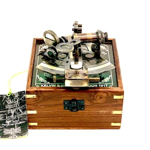 May include: A brass sextant in a wooden box with a green glass face. The sextant is labelled "Kelvin & Hughes London 1917".