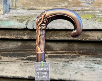 May include: A copper-colored walking stick with a decorative handle featuring a floral design. The stick is black and has a tag attached that reads "Delivery within 3 days" and "Ministry of Antiques UK Seller Same Day Dispatch".