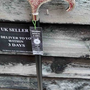 K&ouml;nnte beinhalten: Ein Gehstock aus schwarzem Holz mit einer silberbeschichteten Grifffl&auml;che. Der Griff ist mit einem komplizierten Blumenmuster verziert. Der Stock lehnt an einer Holzwand mit einem Schild, auf dem steht "UK SELLER DELIVER TO YOU WITHIN 3 DAYS VIA ROYAL MAIL RECORDED DELIVERY".