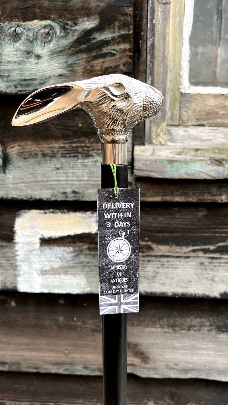 May include: A silver rabbit head walking stick with a black shaft. The stick has a tag attached that says "Delivery within 3 days" and "Ministry of Antiques UK Seller Same Day Dispatch".