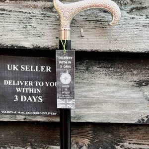 K&ouml;nnte beinhalten: Ein Gehstock aus schwarzem Holz mit einem verzierten, versilberten Griff. Der Stock lehnt an einer Holzwand mit einem Schild, auf dem steht "UK Seller Deliver to you within 3 days via Royal Mail Recorded Delivery". Ein am Stock befestigtes Schild tr&auml;gt die Aufschrift "Delivery within 3 days Ministry of Antiques UK Seller Same Day Dispatch".