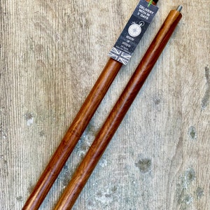 May include: Two brown wooden walking sticks with black metal tips. The sticks are on a wooden surface. A tag is attached to one stick that says "Delivery within 3 days" and "Ministry of Antiques, Established 1942, London, England".