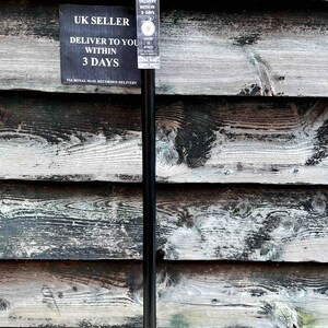 K&ouml;nnte beinhalten: Ein schwarzer Gehstock mit einem silbernen Griff. Der Griff hat ein dekoratives Design. Der Stock steht aufrecht an einer Holzwand.