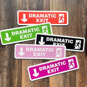 May include: A collection of rectangular signs with the words "DRAMATIC EXIT" in white text. Each sign has a downward-pointing arrow and a graphic of a person running towards an exit. The signs are in red, green, black, pink, and magenta.