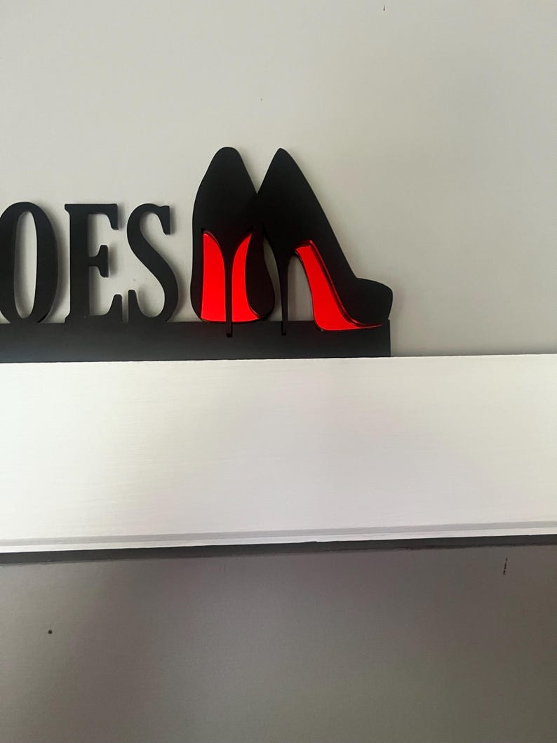 May include: Black wooden sign with the word "Shoes" and two black high heel shoes with red soles.
