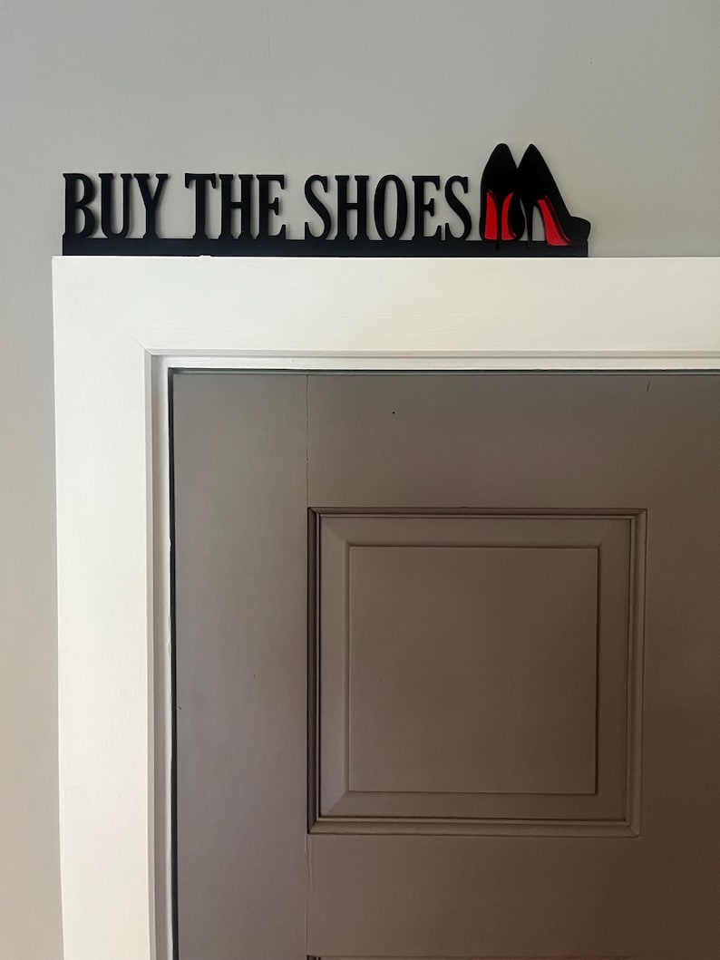May include: Black wooden sign with the text "BUY THE SHOES" and a pair of red high heels.