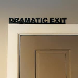 Puede incluir: Una puerta blanca con un letrero negro encima que dice "Dramatic Exit".