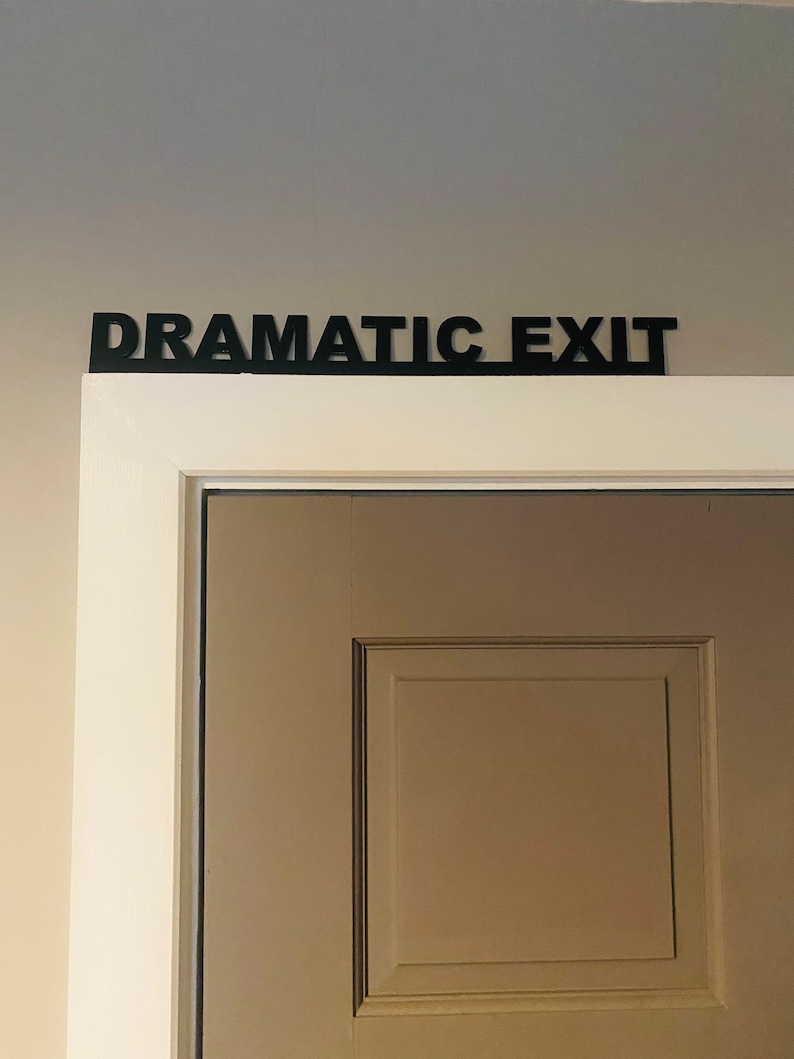 Puede incluir: Una puerta blanca con un letrero negro encima que dice "Dramatic Exit".