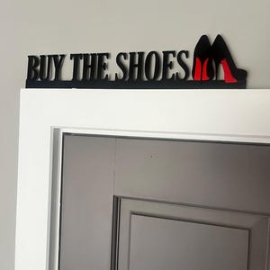 May include: Black wooden sign with the text "BUY THE SHOES" and two red high heel shoes.