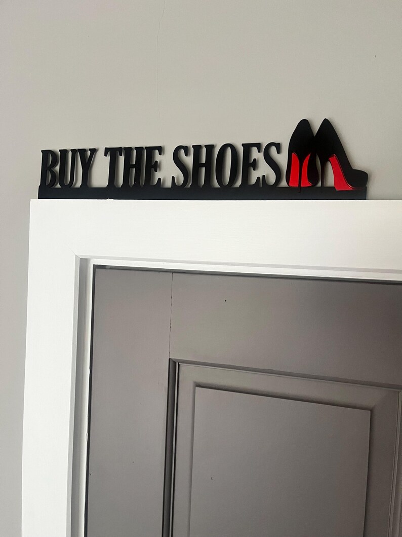 May include: Black wooden sign with the text "BUY THE SHOES" and two red high heel shoes.