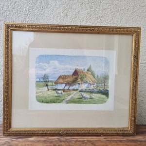 May include: A framed watercolour painting depicting a white cottage with a thatched roof. The cottage is surrounded by a green field with a few sheep grazing. The sky is blue with white clouds.