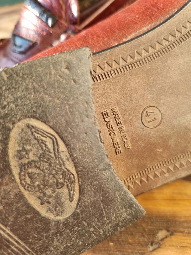 May include: Close-up of the bottom of a brown leather shoe with a brown rubber sole. The sole has a pattern of small triangles and the text "Made in Italy Elastomeree" is printed on the side. The shoe size is 41.