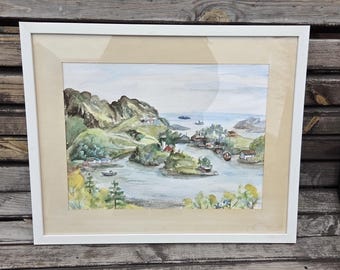May include: Watercolor painting of a coastal landscape in a white frame. The artwork depicts a serene scene with green hills, a calm body of water, small boats, and houses. The sky is a soft blue, and the overall color palette is muted.