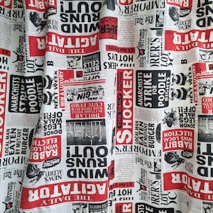 May include: Newspaper-themed fabric with a repeating pattern of headlines, articles, and illustrations in black, white, and red. The text includes words like "Agitator," "Strike," and "Shocker."