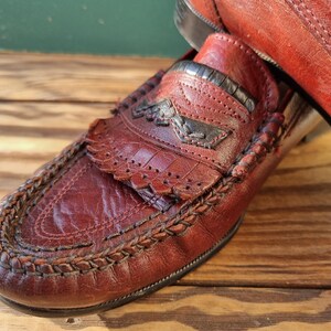 May include: A pair of brown leather loafers with a braided trim and a decorative stitch pattern. The loafers have a pointed toe and a low heel.