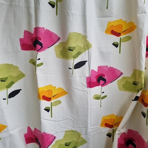 May include: White fabric with a repeating pattern of colorful flowers. The flowers are in shades of pink, yellow, and green, with black accents. The floral design is set against a white background.