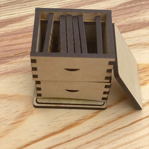 May include: A wooden box with a lid, divided into multiple compartments. The box is made of light brown wood and has a dark brown finish. The lid is open and the compartments are visible.