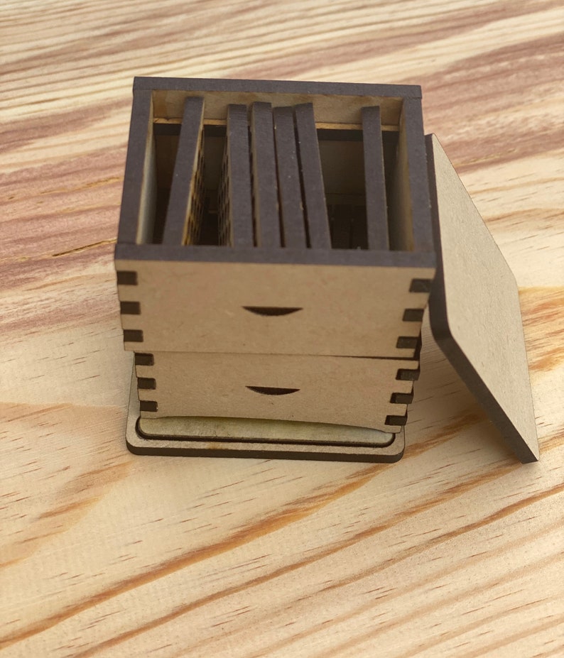 May include: A wooden box with a lid, divided into multiple compartments. The box is made of light brown wood and has a dark brown finish. The lid is open and the compartments are visible.
