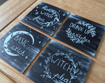 Può includere: Quattro sottobicchieri quadrati neri con lettere bianche. I sottobicchieri presentano diverse frasi a tema streghe, tra cui "Resting Witch Face", "Basic Witch", "Drink Up Bitches" e "Witch Please".