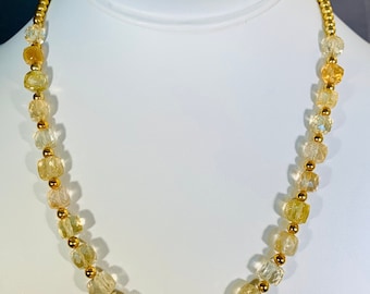 May include: A gold necklace with light yellow faceted beads. The necklace is on a white mannequin bust.