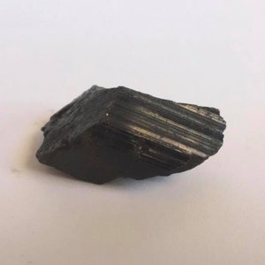 May include: A black, rough, and jagged piece of black tourmaline crystal.