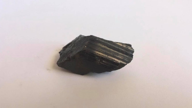 May include: A black, rough, and jagged piece of black tourmaline crystal.