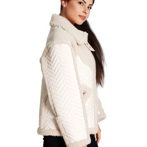 May include: A white faux fur jacket with a quilted chevron pattern on the sleeves and a stand-up collar.