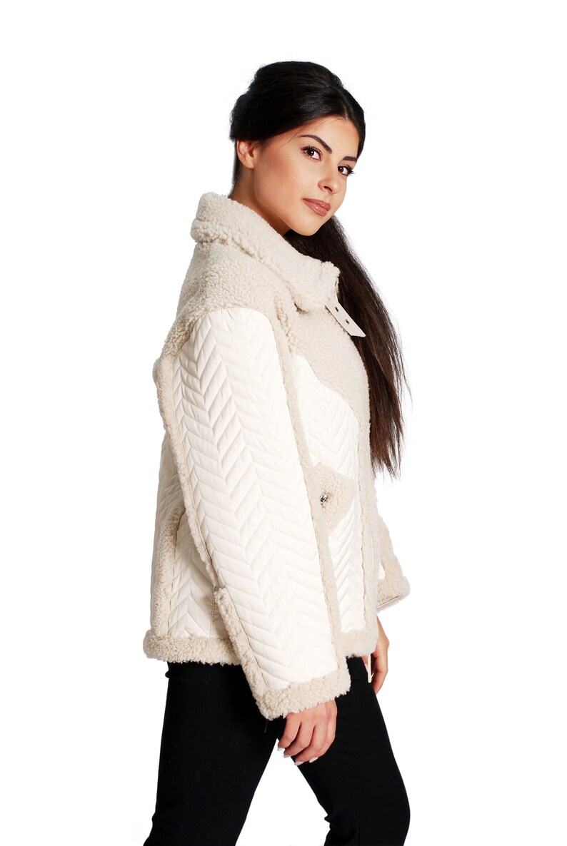 May include: A white faux fur jacket with a quilted chevron pattern on the sleeves and a stand-up collar.