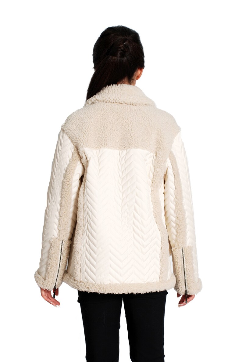 May include: A white quilted jacket with a sherpa collar and trim. The jacket has a chevron pattern on the front and back.