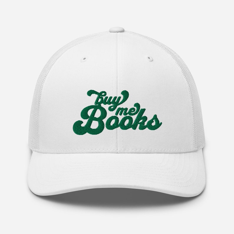May include: White trucker hat with a green embroidered design that says "Buy Me Books" in a retro font.