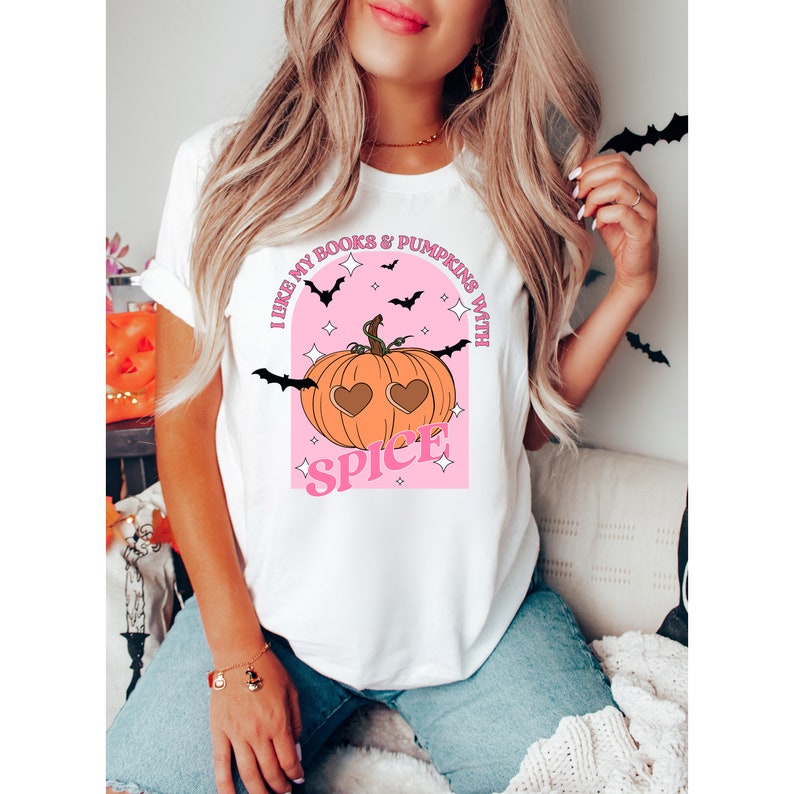 May include: White t-shirt with a pink and orange graphic of a pumpkin with heart-shaped eyes and the text "I like my books & pumpkins with spice".