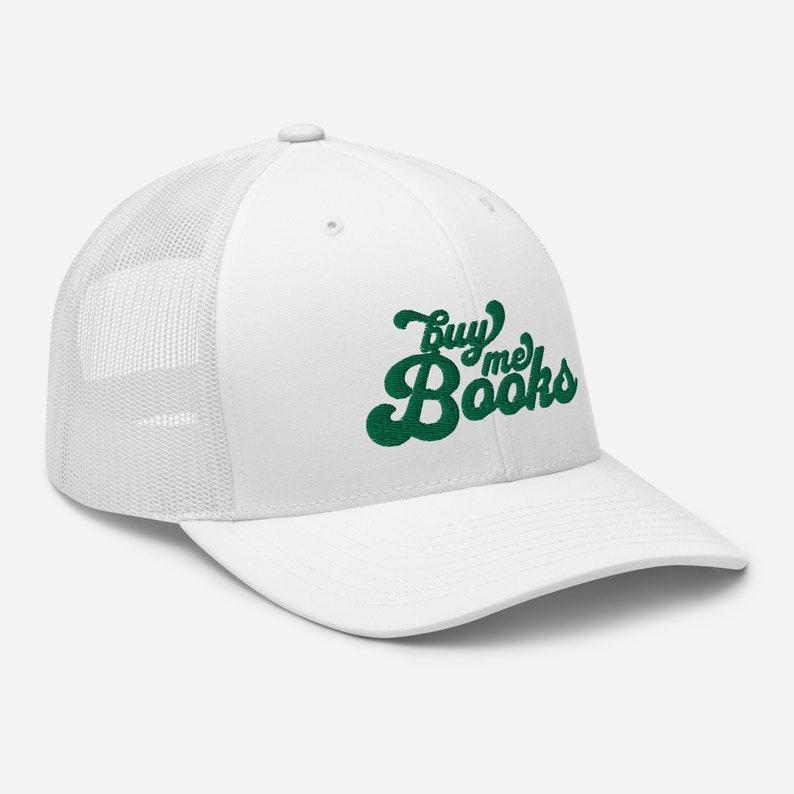 May include: White trucker hat with a green embroidered design that says "Buy me Books" in a retro font.