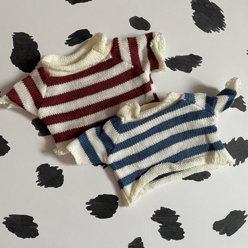 May include: Two striped knitted shirts, one with red and white stripes and one with blue and white stripes.